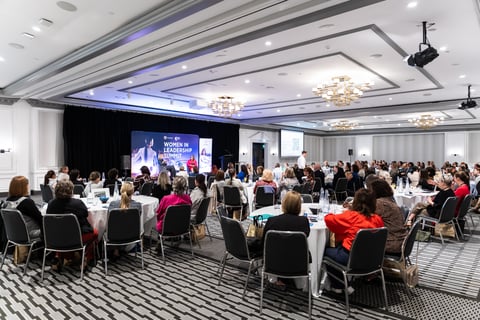 Delegates seated at round tables during a Women in Leadership Summit keynote