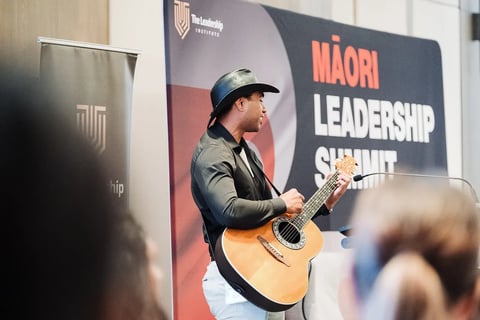 A waiata with guitar on stage at the Māori Leadership Summit 2025