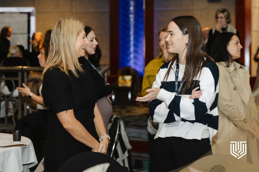 Professional women networking at a conference, engaged in conversation