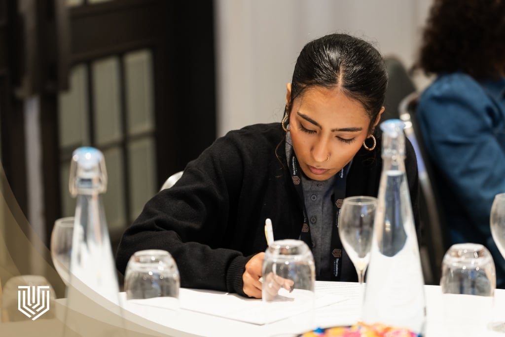 Two professionals in a mentoring conversation, one taking notes