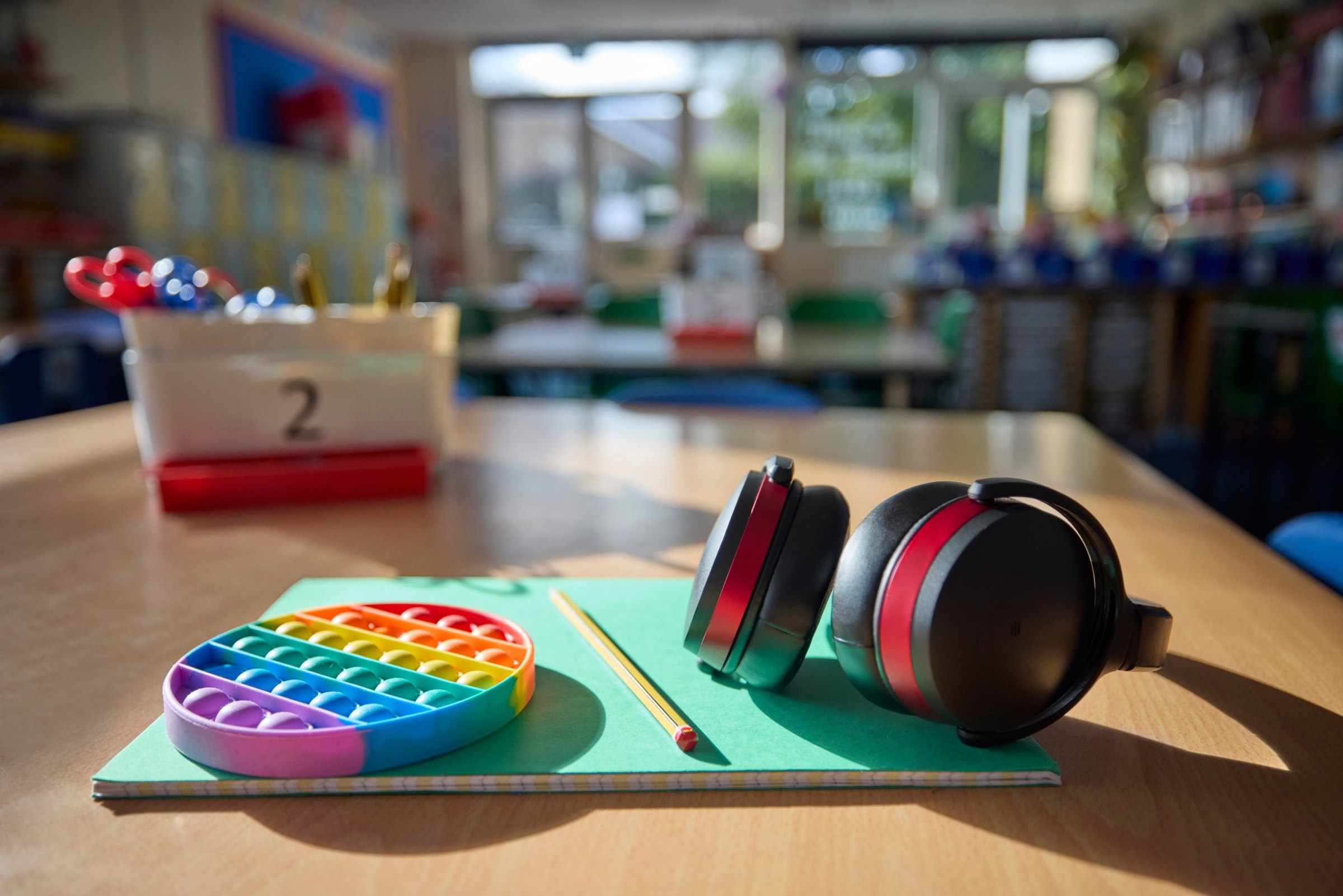 Ear defenders and a fidget toy on a desk in a primary classroom