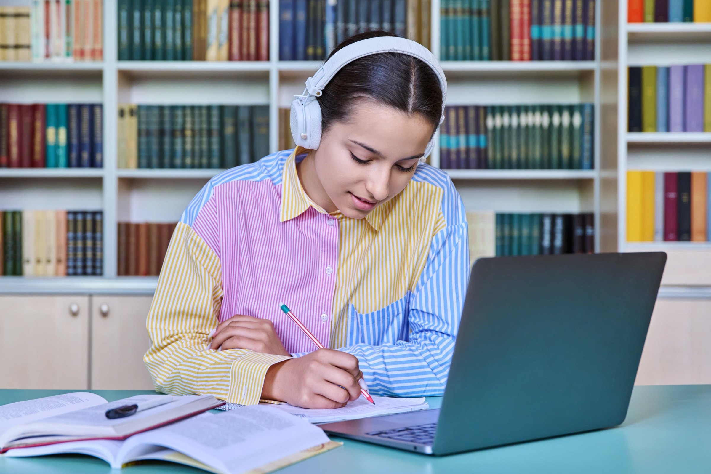 A secondary student with headphones working alone in the school library