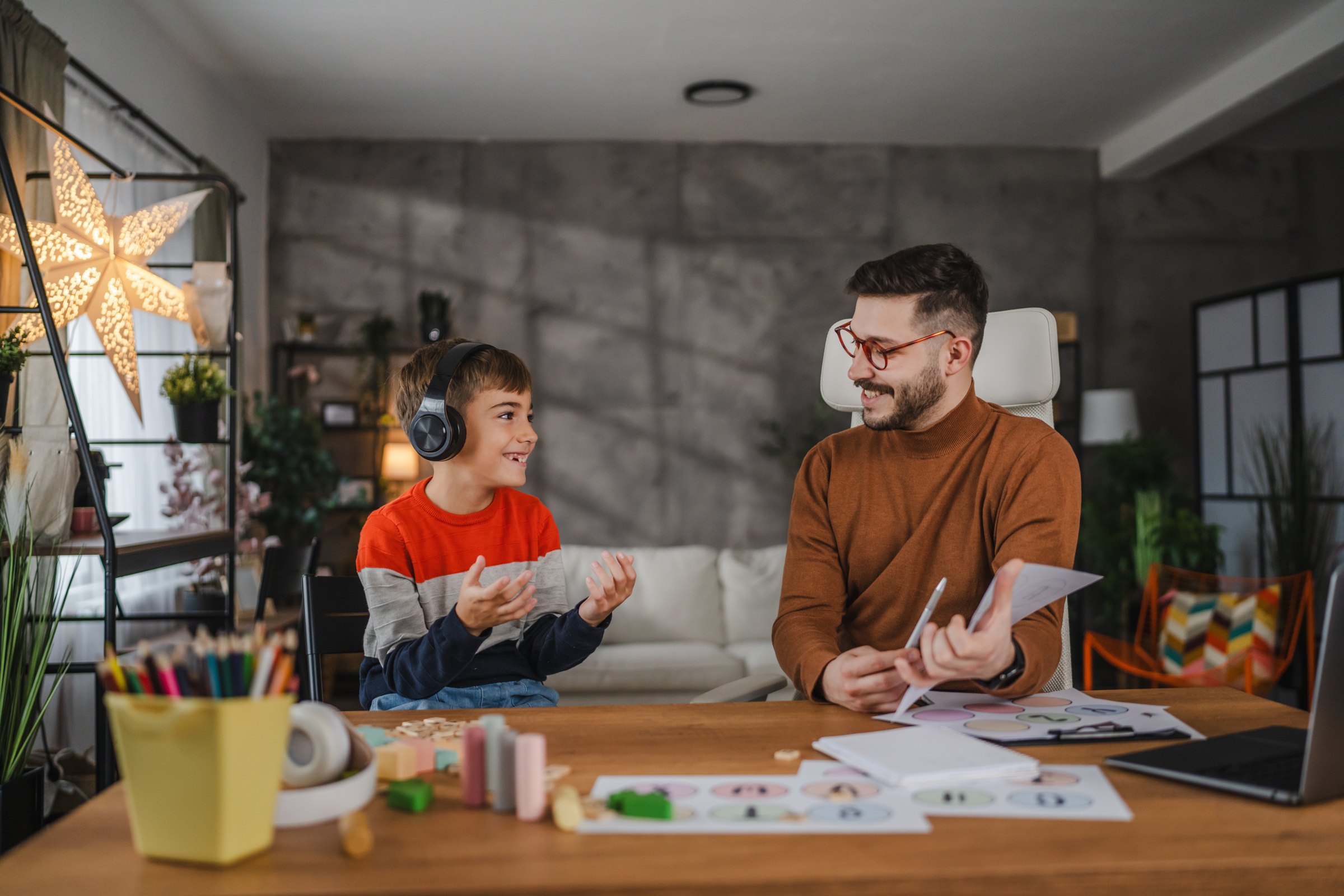A boy wearing headphones working one to one with a therapist